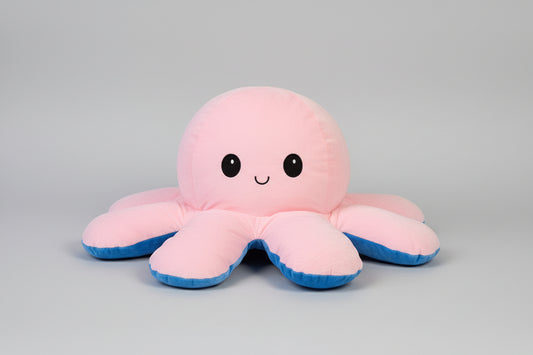 Pink and blue reversible octopus plush toy with happy face on a white background.