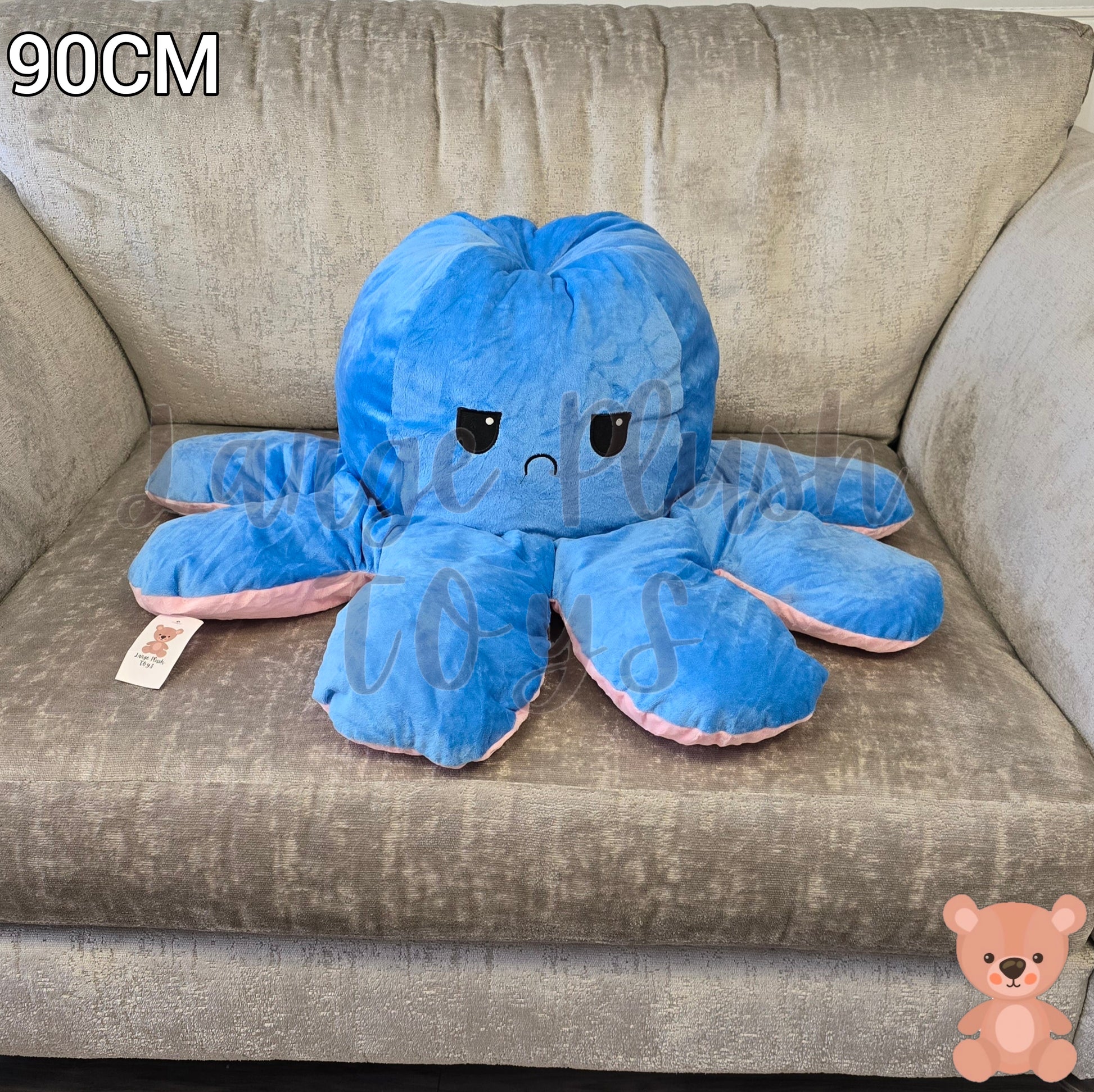 90cm blue and pink reversible octopus plush toy with angry face displayed on a grey sofa.