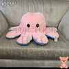 90cm pink and blue reversible octopus plush toy with happy face displayed on a grey sofa.