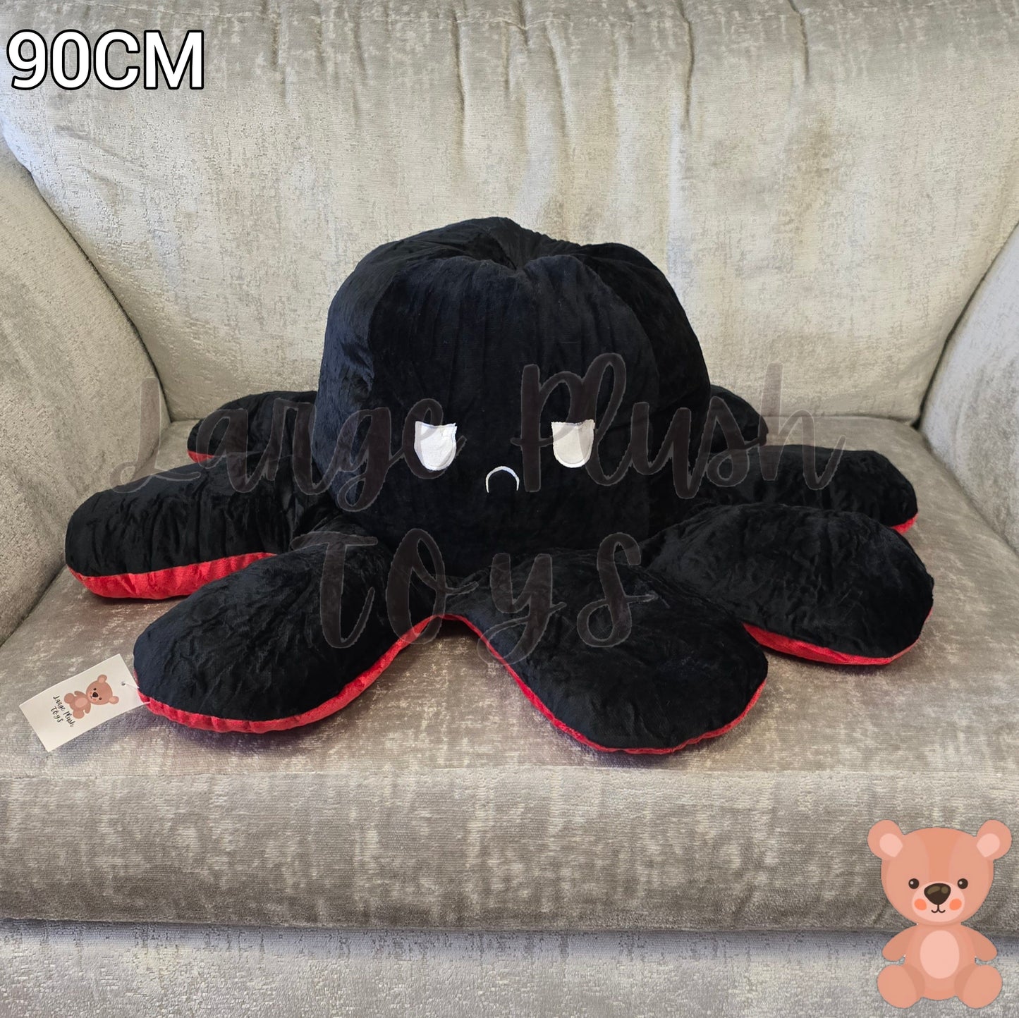 90cm reversible octopus plush toy with angry black face and red trim displayed on a grey armchair.