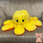 90cm yellow and orange reversible octopus plush toy with happy face on an armchair.