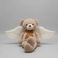 Angel teddy bear plush toy with white wings and brown ribbon bow sitting on a light grey background