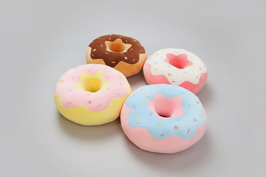 Collection of donut plush pillows featuring chocolate, pink, blue and vanilla frosting designs with colourful sprinkles.