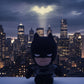 Batman plush toy displayed in front of Gotham City skyline at night with illuminated city lights