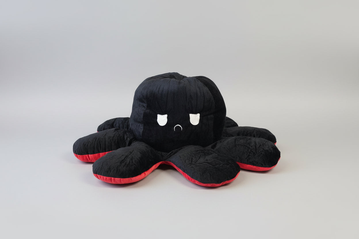 Black and red reversible octopus plush toy with angry expression displayed on a white background.