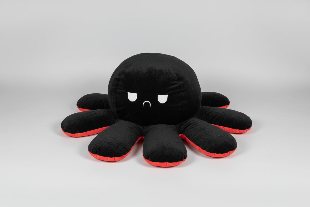 Black and red reversible octopus plush toy with frowning face displayed on a white background.