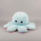 Blue and pink reversible octopus plush toy with angry face on a light grey background.