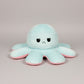 Blue and pink reversible octopus plush toy with angry face on a grey background.