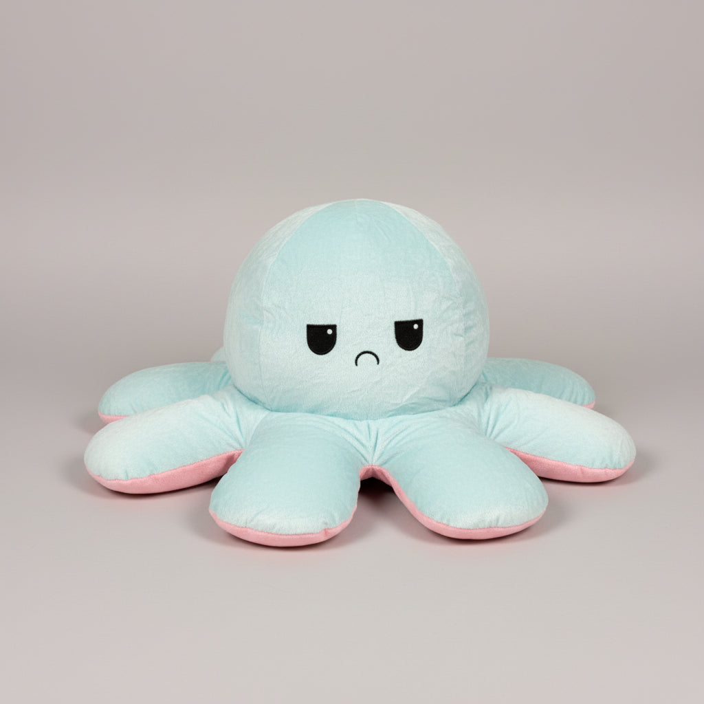 Blue and pink reversible octopus plush toy with angry face on a grey background.