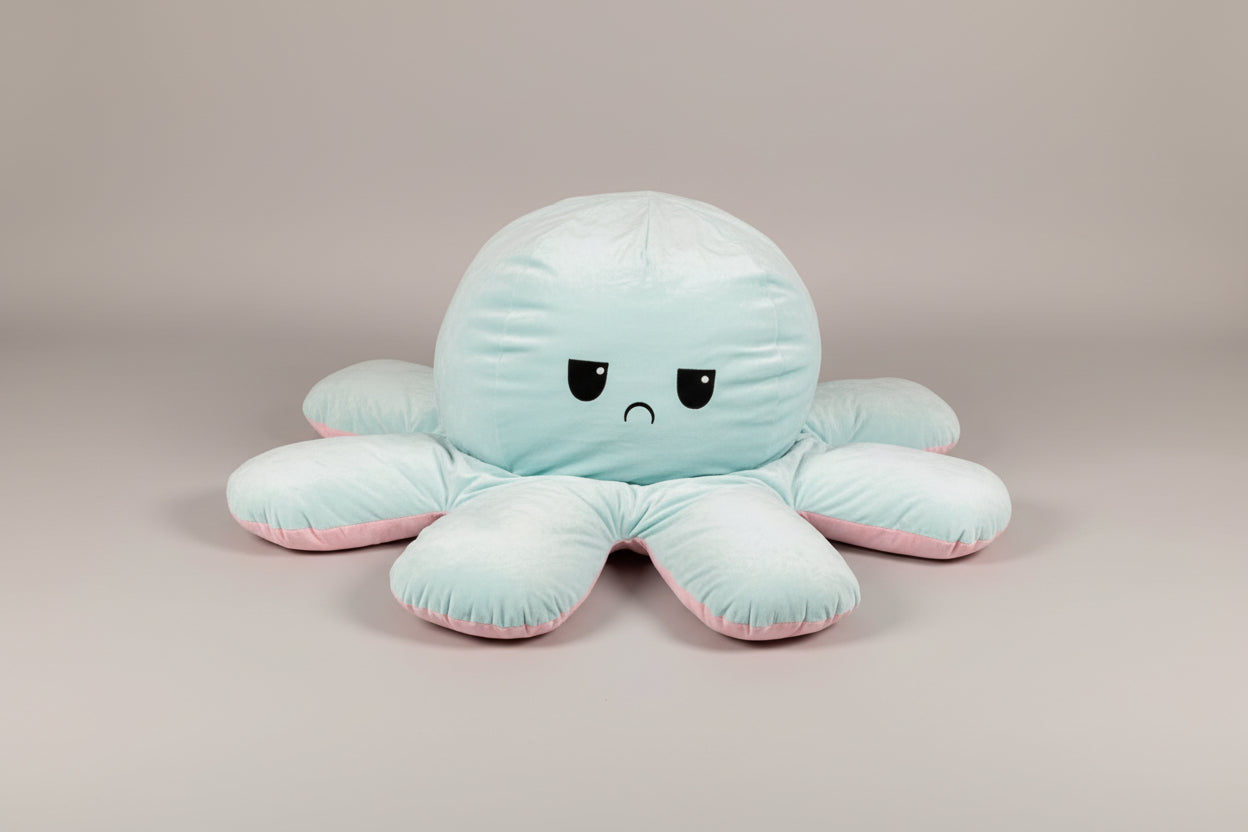 Blue and pink reversible octopus plush toy with angry face in a studio product photo on a light grey background.