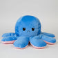 Blue and pink reversible octopus plush toy with sad face on a white background.