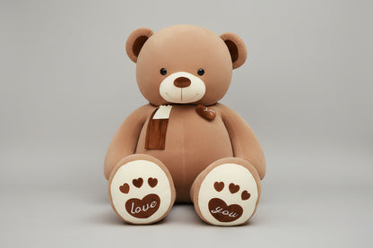Brown teddy bear plush toy with heart paw details, soft scarf and cuddly stuffed design.