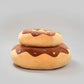 Stacked chocolate donut plush pillows with sprinkle frosting design and soft cushioned filling.