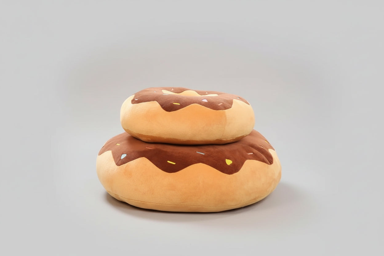 Stacked chocolate donut plush pillows with sprinkle frosting design and soft cushioned filling.