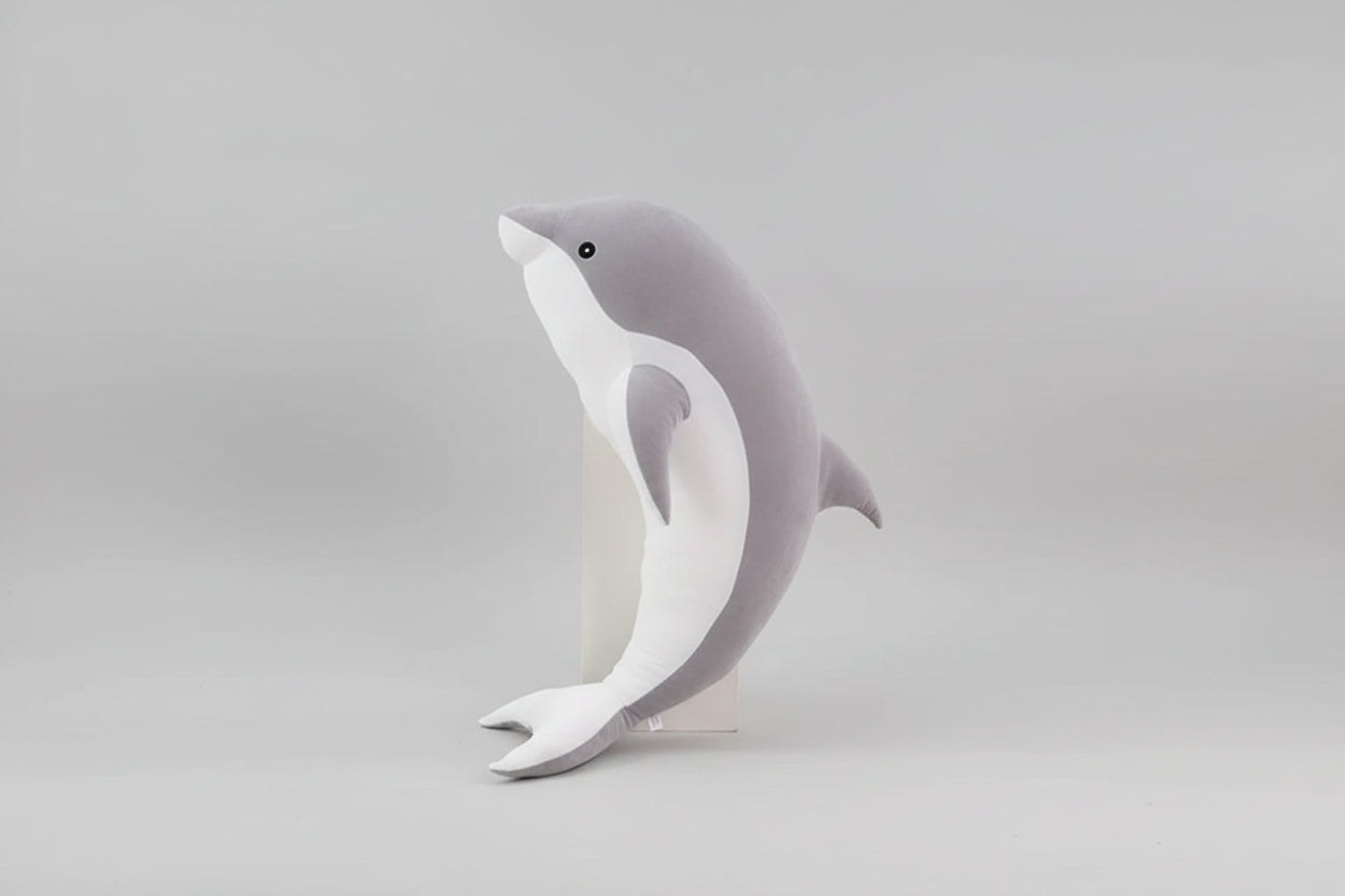 Grey and white dolphin plush toy standing upright on a light grey background.