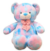 Large pastel teddy bear plush toy in pink and blue colours with a pink bow displayed on a white background