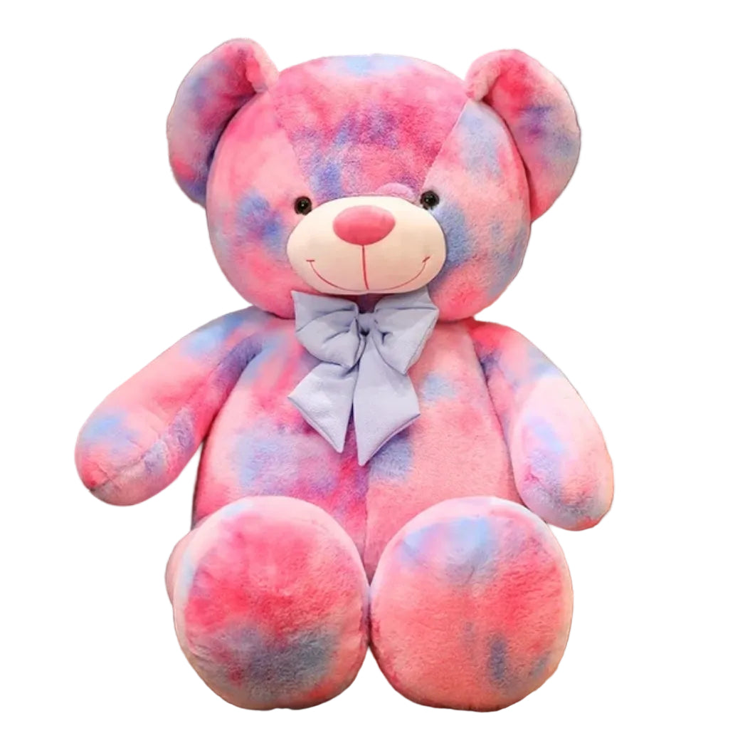 Large pastel teddy bear plush toy in pink and purple colours with a decorative bow displayed on a white background