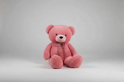 Large pink teddy bear plush toy with a satin bow sitting on a grey background