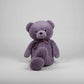Large purple teddy bear plush toy with a satin bow sitting on a light grey background