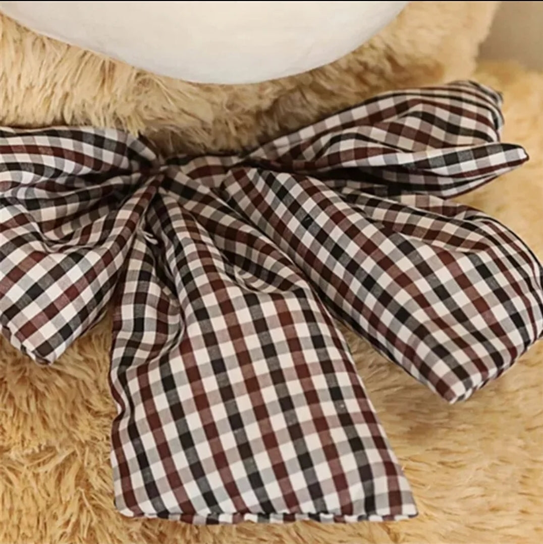 Close up of the decorative checkered bow tie on a large teddy bear plush toy showing soft fabric details.