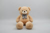 Large light beige teddy bear plush toy with decorative bow tie soft stuffed animal gift for children and adults.