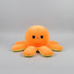 Orange reversible octopus plush toy with angry face on a light grey background.
