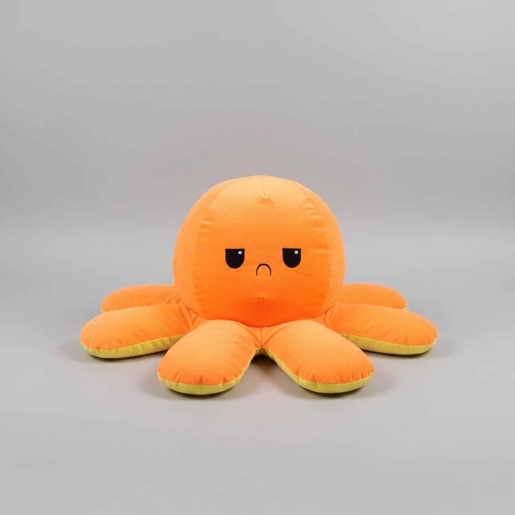 Orange reversible octopus plush toy with angry face on a light grey background.