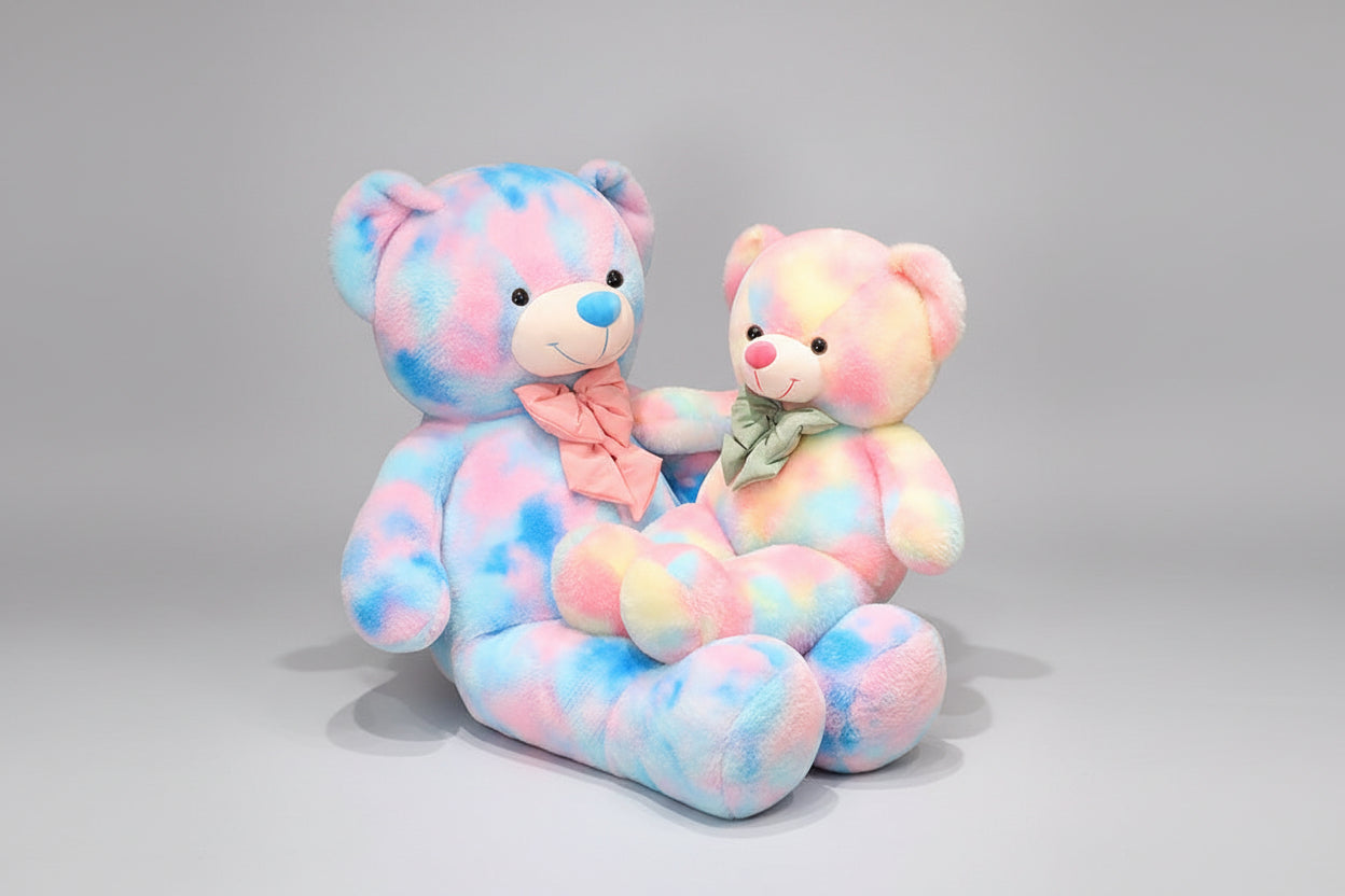 Two pastel teddy bear plush toys in pink blue and rainbow colours sitting together on a neutral background