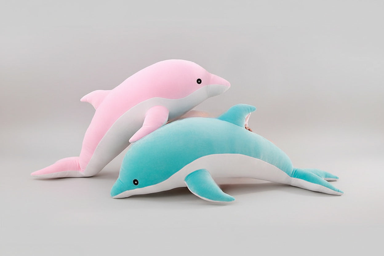 Pink and blue dolphin plush toys layered together on a light grey background