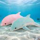 Pink and blue dolphin plush toys displayed in an underwater ocean scene with coral reef and tropical fish