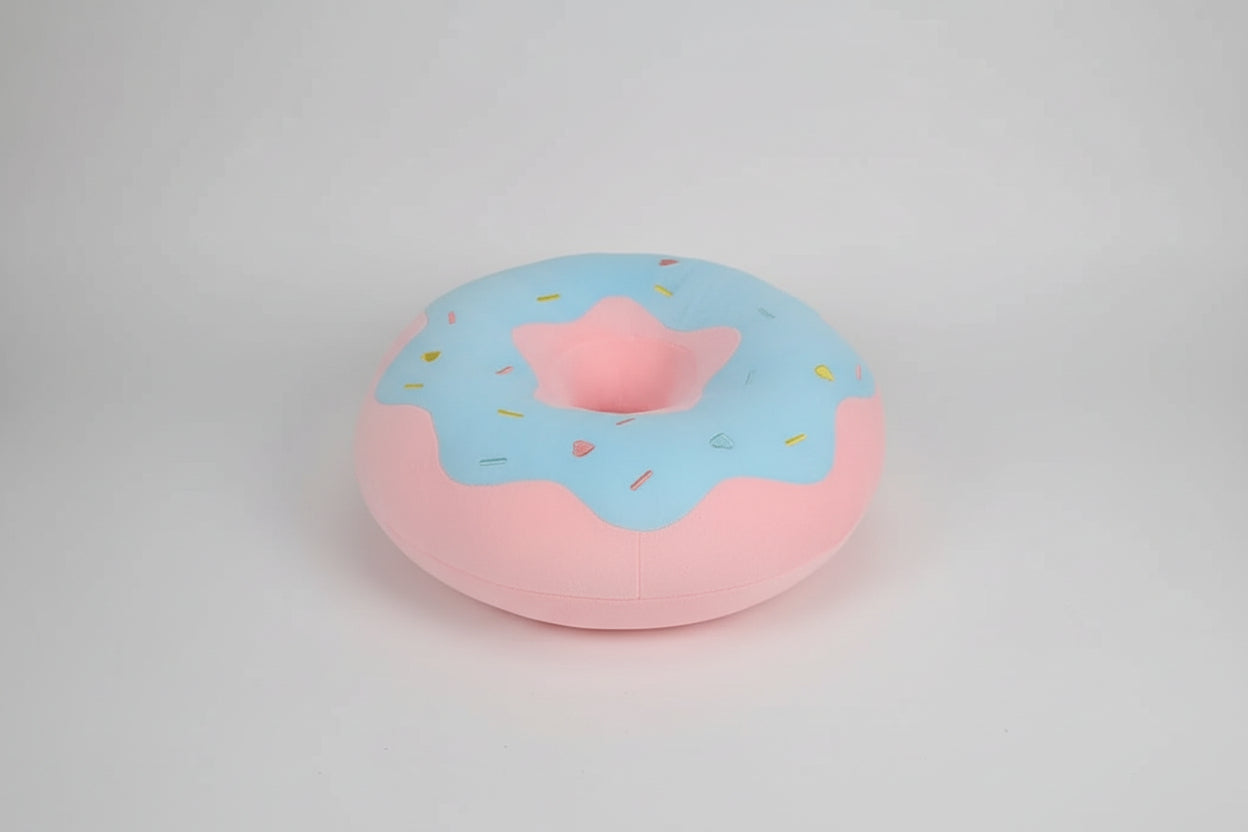 Pink donut plush pillow with blue frosting and colourful sprinkle design made from soft plush fabric.
