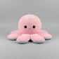 Pink and blue reversible octopus plush toy with happy face on a light grey background.