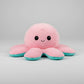 Pink and blue reversible octopus plush toy with happy face on a grey background.
