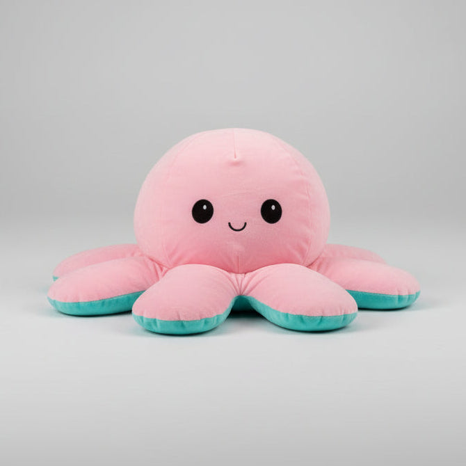 Pink and blue reversible octopus plush toy with happy face on a grey background.