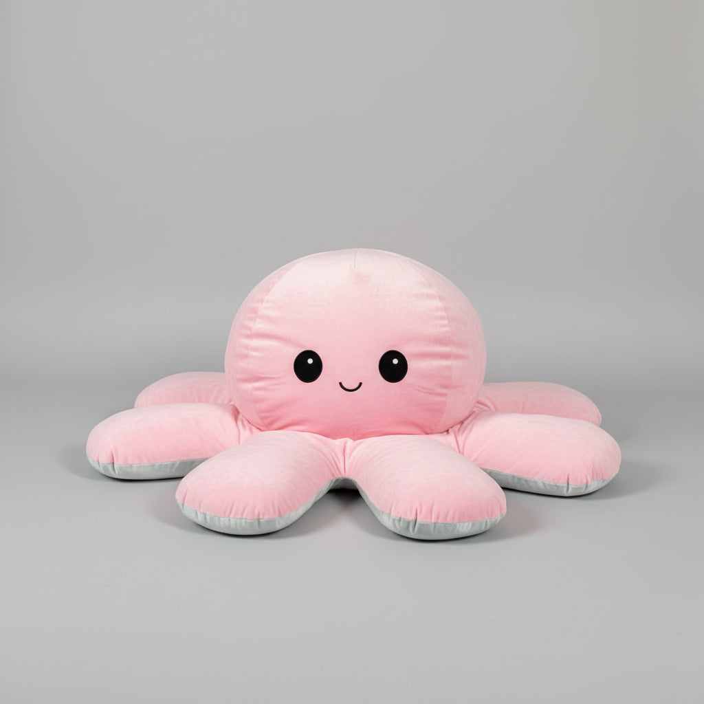Pink and blue reversible octopus plush toy with happy face in a studio product photo on a light grey background.