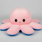 Pink and blue reversible octopus plush toy with happy face on a white background.