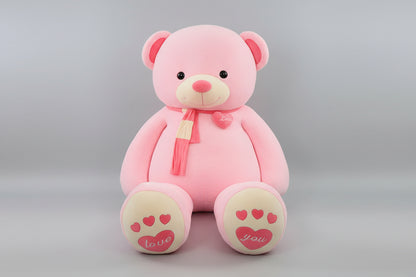 Pink teddy bear plush toy with love heart details, soft scarf and embroidered paw design.