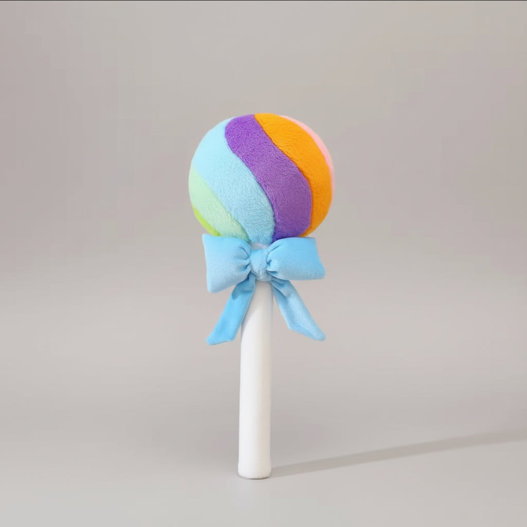 Rainbow lollipop plush toy with blue ribbon bow on a light grey background.