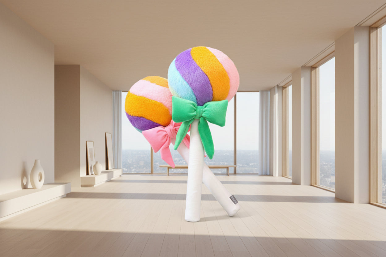 Rainbow lollipop plush toys with colourful bows standing in a modern living room with floor-to-ceiling windows.
