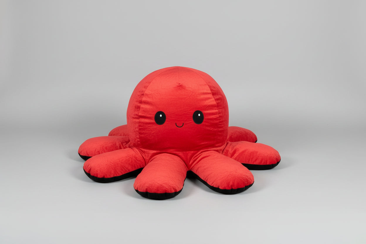 Red and black reversible octopus plush toy with smiling face displayed on a white background.