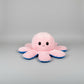 Small pink and blue reversible octopus plush toy with happy face on a white background.