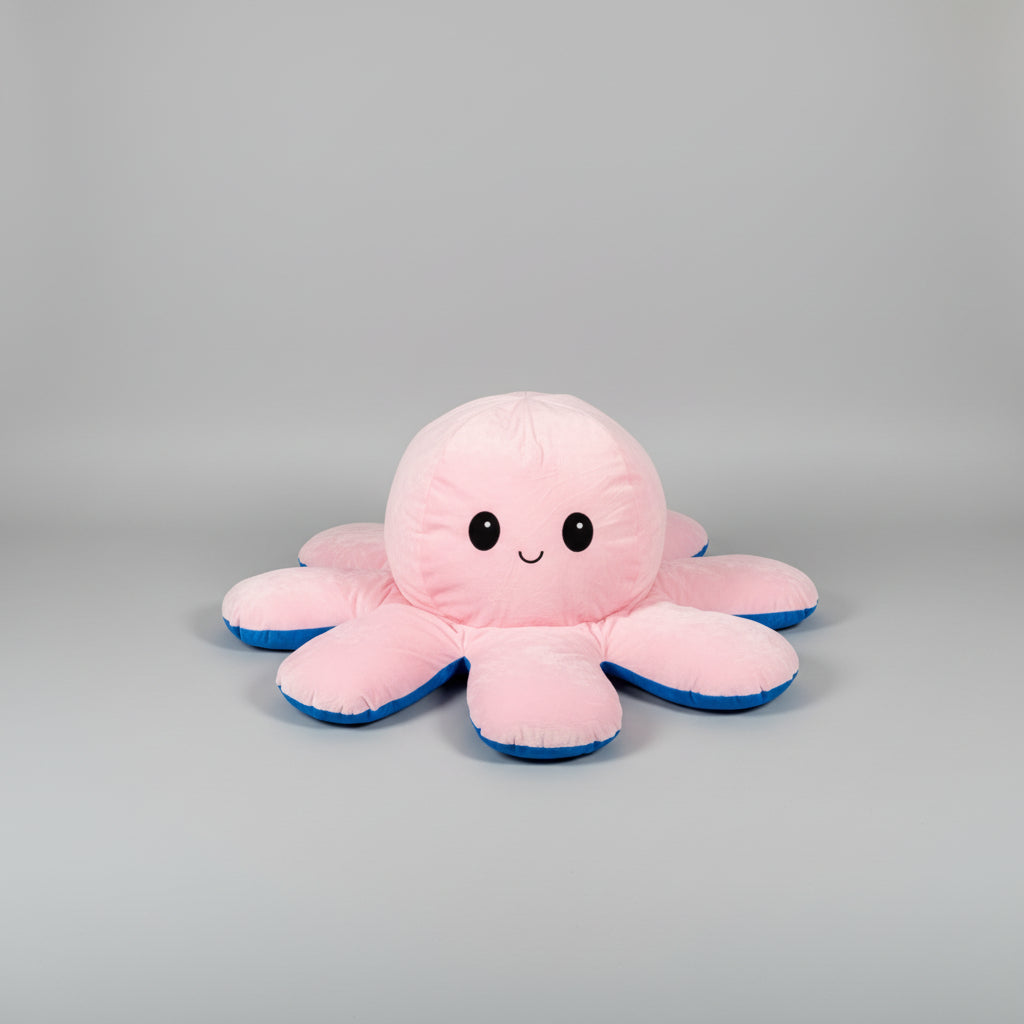 Small pink and blue reversible octopus plush toy with happy face on a white background.