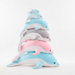 Stacked dolphin plush toys in blue, pink and grey colours displayed on a white background