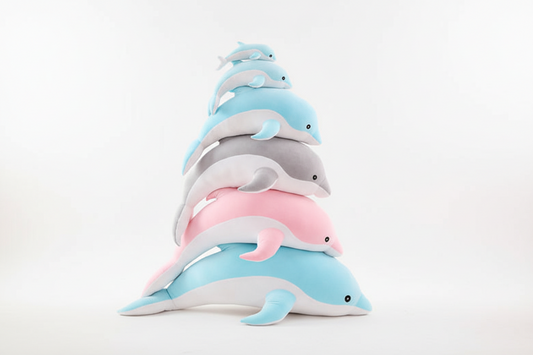Stacked dolphin plush toys in blue, pink and grey colours displayed on a white background