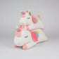 White unicorn plush toys with rainbow horns and pastel wings stacked on a light grey background.