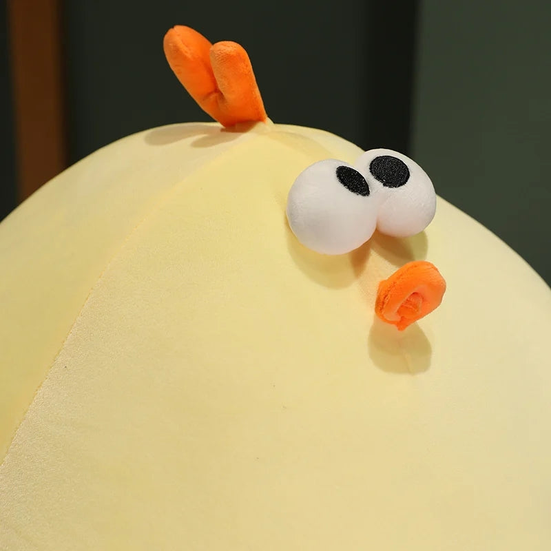 Close-up of a yellow chicken plush toy showing embroidered eyes, beak and soft stuffed fabric details.