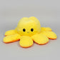 Yellow and orange reversible octopus plush toy with happy face on a light grey background.