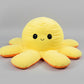 Yellow and orange reversible octopus plush toy with happy face on a light grey background.