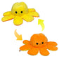 Yellow and orange reversible octopus plush toy with happy and sad mood expressions on a white background.